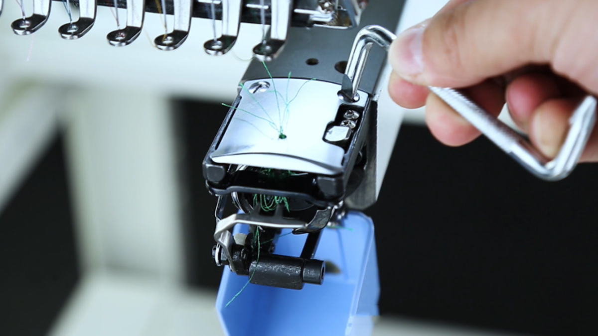 Using a Z-shaped wrench to turn the screws on the needle plate for cleaning the bobbin area