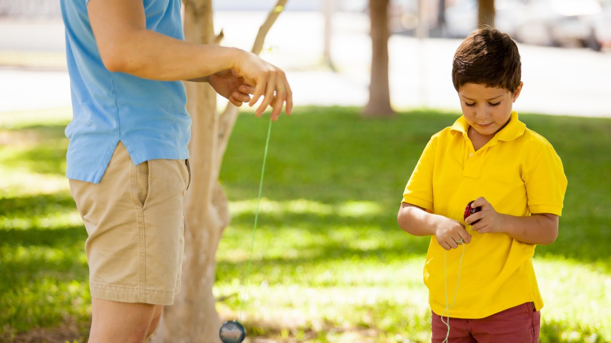 An adult and a child playing with a yo-yo.